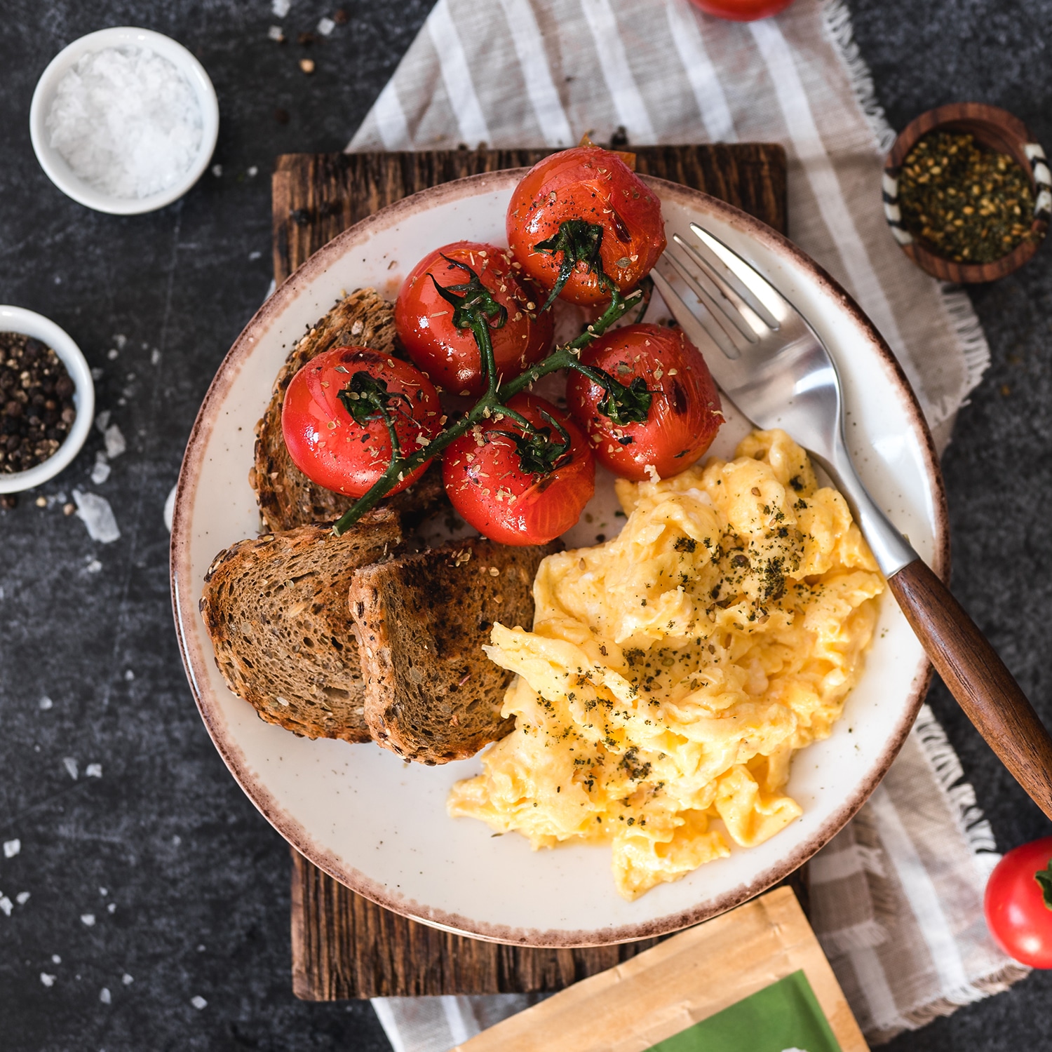 Rührei garniert mit Zaatar, serviert mit gerösteten Tomaten und Brot